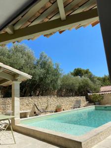 a swimming pool with a table and chairs next to a house at les-pepites-de-badou présentent La Gravière in Le Barroux