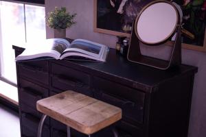 a desk with a mirror and a book and a stool at 31B Urban Stays in Norwich