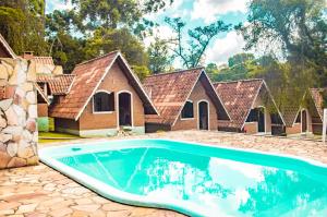 a house with a swimming pool in front of it at Pousada Vale Verde in Monte Verde