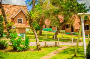 a house with a yard with trees and a fence at Pousada Vale Verde in Monte Verde