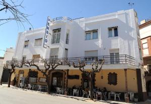 a white building with tables and chairs in front of it at Pension Subirats Perello in Perelló