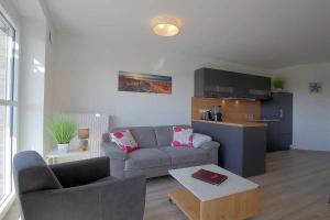 ein Wohnzimmer mit einem Sofa und einem Tisch in der Unterkunft de Seedüwel Carna 101 in Dorum Neufeld