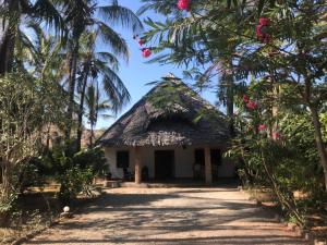 a small house with a thatched roof and palm trees at Watamu Sunrise Villa in Watamu