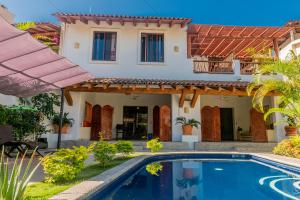 eine Villa mit Swimmingpool vor einem Haus in der Unterkunft Villas Sunrisa in Zihuatanejo