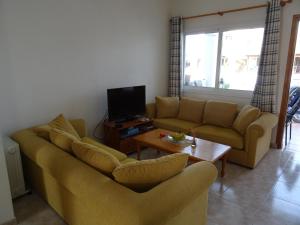 een woonkamer met een bank en een tv bij Andromeda Beach house in Polis Chrysochous