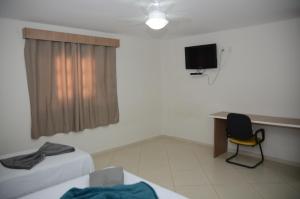 una habitación con un escritorio y una silla y un televisor en Hotel Canaã Express, en Jarinu 35 fotos más