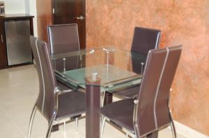 a glass table and four chairs in a room at Premier Hotel Suites in Ciudad Obregón