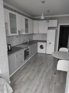 eine Küche mit weißen Schränken und einem Tisch darin in der Unterkunft Апартаменти Люкс2 in Chmelnyzkyj