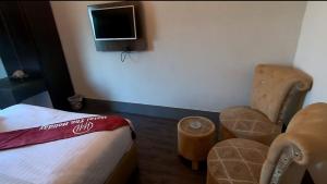 a room with a bed and two chairs and a tv at Hotel The Holiday in Lahore