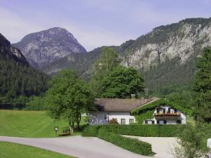una casa en un campo con montañas en el fondo en Hotel- Pension Oechsner, en Bad Reichenhall