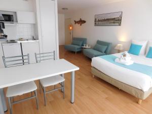 1 dormitorio con cama, mesa y cocina en Résidence New Rochelle, en La Rochelle