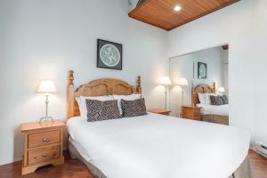 a bedroom with a large white bed and two lamps at Rainbow by Outpost Whistler in Whistler