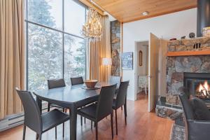 a dining room with a table and chairs and a fireplace at Rainbow by Outpost Whistler in Whistler