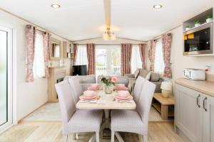 een keuken en eetkamer in een caravan met een tafel en stoelen bij Lilly Pad in South Cerney