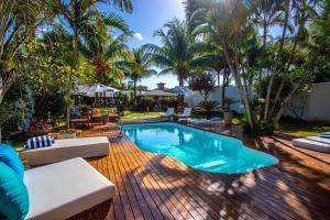 a swimming pool in a backyard with palm trees at Búzios House Oficial in Búzios