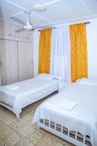 two beds in a room with yellow curtains at Aqui me quedo in Cartagena de Indias
