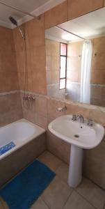 a bathroom with a sink and a tub and a mirror at Belgrano Apartment con cochera in Mendoza