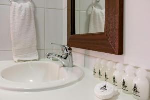 y baño con lavabo, espejo y algunas botellas de leche. en San Ignacio Suite, en Santiago