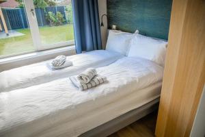 un letto con asciugamani e finestra di Vakantiehuis in hét bomendorp van de Veluwe a Putten