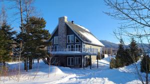 Une grande maison dans la neige en hiver dans l'établissement Condo-chalet de la Vallée d'Édouard, à LʼAnse-Saint-Jean