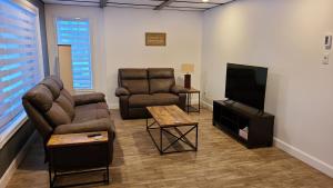 sala de estar con sofás y TV de pantalla plana. en Condo-chalet de la Vallée d'Édouard, en L'Anse-Saint-Jean