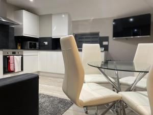 cocina con mesa de cristal y sillas blancas en Amazing CENTRAL High Street Self contained Apartments by SYL, en Watford