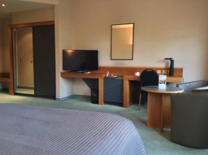 a hotel room with a bed and a desk with a television at Hotel ABBEY in Grimbergen