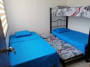 um quarto com 2 beliches e lençóis azuis em Apartamento familiar para un buen descanso con WiFi em Ricaurte