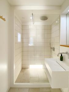 uma casa de banho branca com um chuveiro e um lavatório. em Grüezi Laax Apartments em Laax