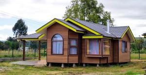 PutemúnCabañas Estero San Juan的田野上带屋顶的小房子