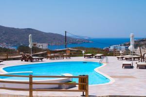 a swimming pool with tables and chairs and the ocean at Amorgion Village in Katapola