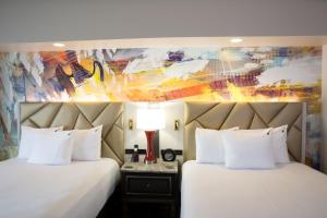two beds in a hotel room with a painting at Hard Rock Hotel & Casino Tulsa in Tulsa