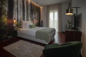 a bedroom with a bed and a tv and a couch at Senhora da Rosa, Tradition & Nature Hotel in Ponta Delgada