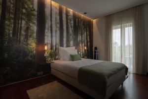 a bedroom with a bed with a large mural of trees at Senhora da Rosa, Tradition & Nature Hotel in Ponta Delgada