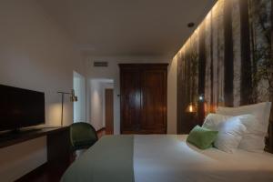 a bedroom with a white bed with a television and a bed sidx sidx at Senhora da Rosa, Tradition & Nature Hotel in Ponta Delgada