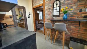 a kitchen with a bar with stools and a brick wall at Magiczne Mieszkanko in Piła