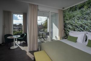a bedroom with a bed and a balcony with a table and chairs at Senhora da Rosa, Tradition & Nature Hotel in Ponta Delgada
