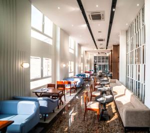 ein Restaurant mit blauen Sofas, Tischen und Fenstern in der Unterkunft Best Western Plus Soaho Douala Airport in Douala