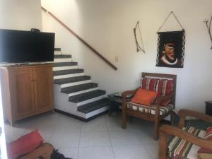 ein Wohnzimmer mit einer Treppe, einem TV und Stühlen in der Unterkunft Para-ti e para-mim! Para todos nós! in Paraty