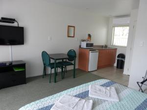 Habitación con cama, mesa y cocina. en Blake Court Motel, en Whangamata