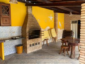 a patio with a brick oven with a table and chairs at Vila Japaraiso-Casa Amarela Próxima ao mar in Japaratinga