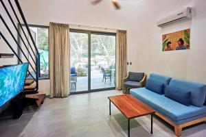 ein Wohnzimmer mit einem blauen Sofa und einem TV in der Unterkunft NATURA Loft Garden in Playa Santa Teresa