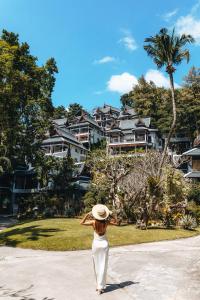 a woman wearing a hat standing in front of a house at Thavorn Beach Village Resort & Spa Phuket in Kamala Beach