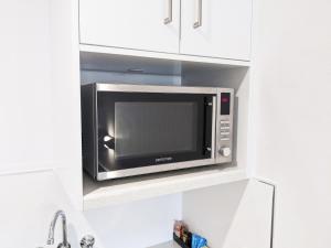 a microwave oven in aessedessed niche in a kitchen at Casa Nostra Motel Mackay in Mackay