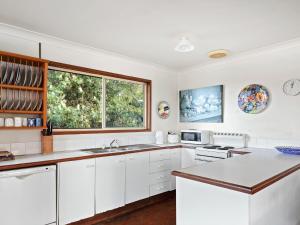 a kitchen with white cabinets and a window at Spacious Adventure Getaway by the Bush & Ocean in Macmasters Beach