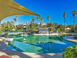 a swimming pool with palm trees and a building at Magenta Shores 1105 in Magenta