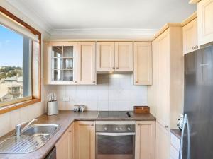 a kitchen with wooden cabinets and a stainless steel refrigerator at Scenic Beachside Apartment, near Bar & Restaurant in Terrigal