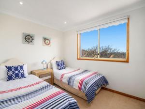 a bedroom with two beds and a window at Scenic Beachside Apartment, near Bar & Restaurant in Terrigal