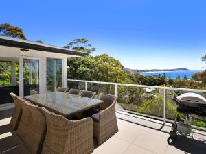a patio with a table and chairs on a balcony at Enjoy Spectacular Oceanviews with BBQ & Airy Space in Terrigal