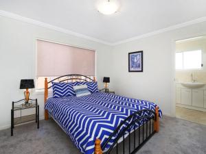 a bedroom with a blue and white bed and a sink at Enjoy Spectacular Oceanviews with BBQ & Airy Space in Terrigal